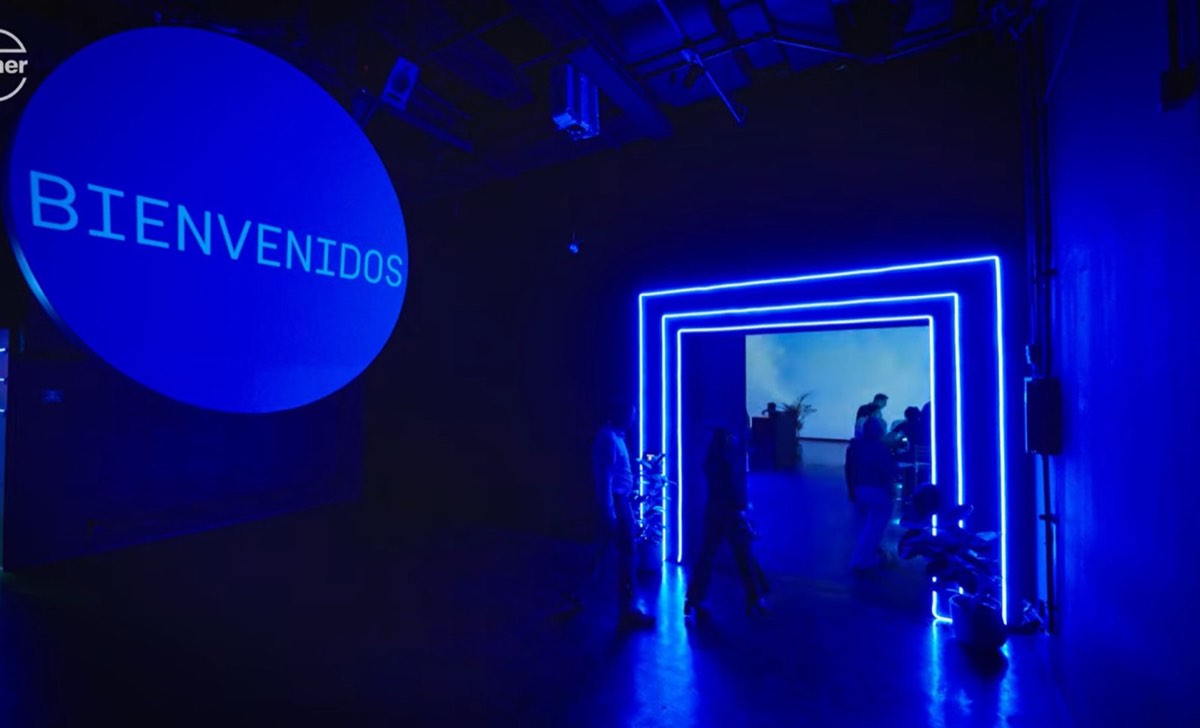 Acceso con túnel de luz neón y proyección de bienvenida a un evento corporativo