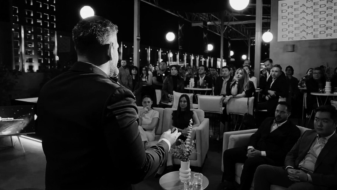 Presentador dirigiéndose a los invitados durante un evento nocturno al aire libre